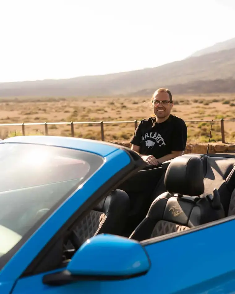 Iván Mora in a blue Mustang convertible